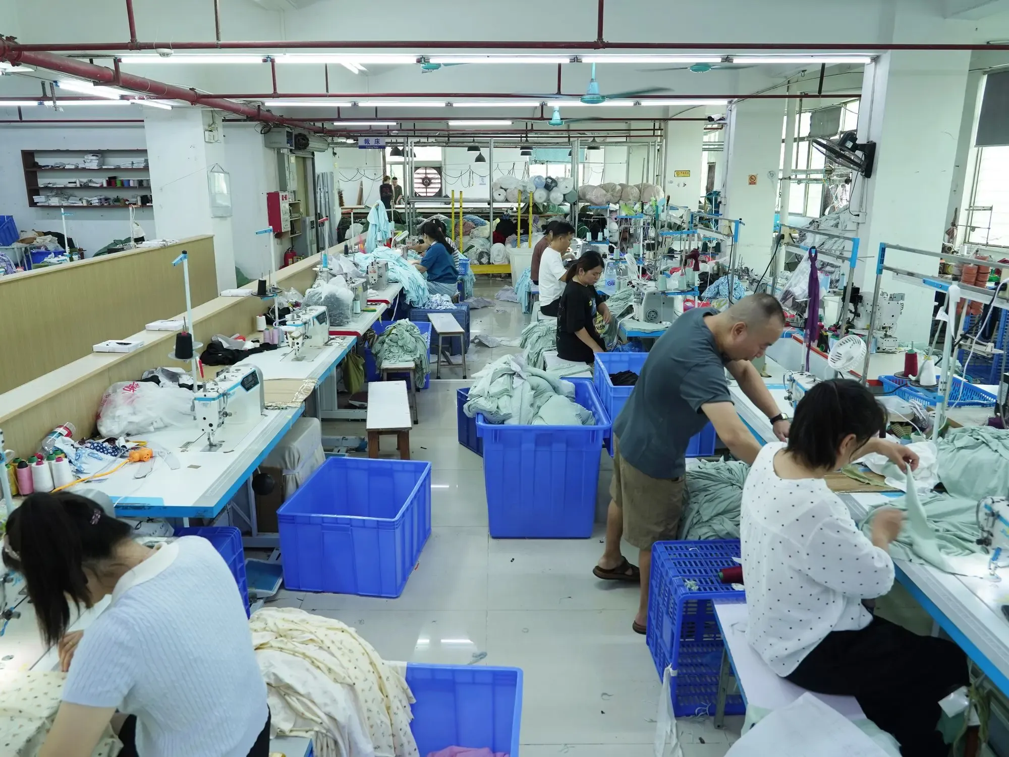 A long sewing line with bins of cut panels beside each station